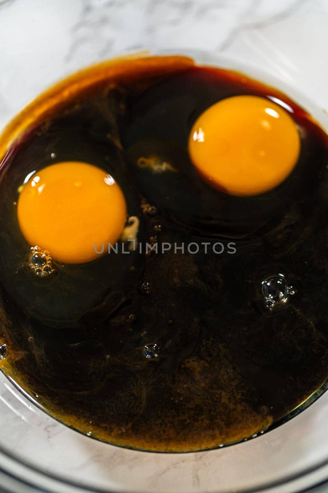 Mixing wet ingredients for Chocolate Gingerbread Cookie Dough, featuring molasses and two eggs in a glass bowl. These wet ingredients provide richness and moisture to the cookie dough.
