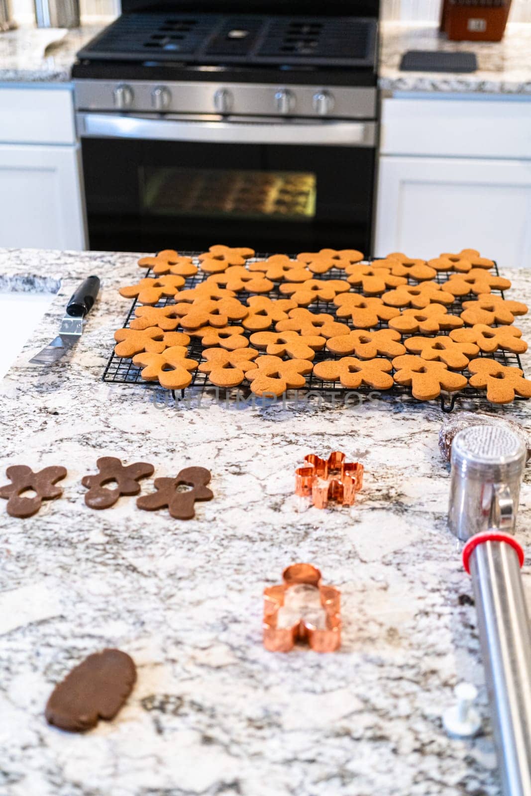 In a contemporary white kitchen, gingerbread cookie dough is skillfully rolled out, setting the stage for a delightful holiday treat.