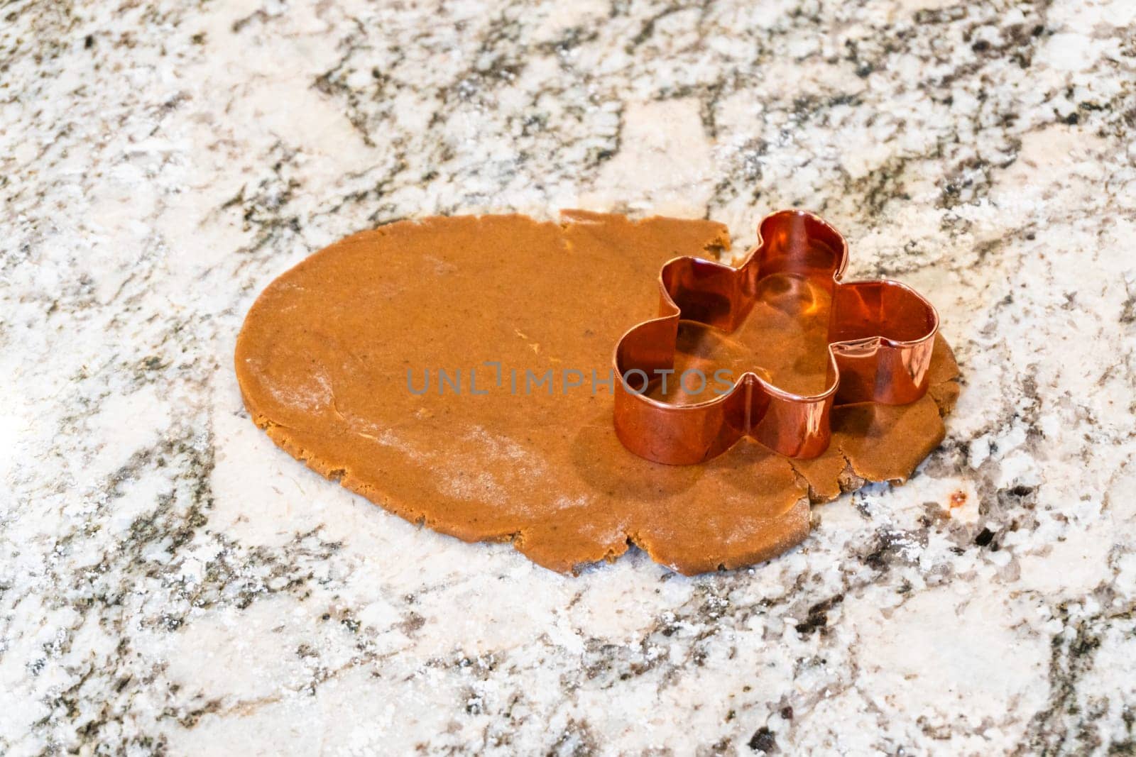 In a contemporary white kitchen, gingerbread cookie dough is skillfully rolled out, setting the stage for a delightful holiday treat.