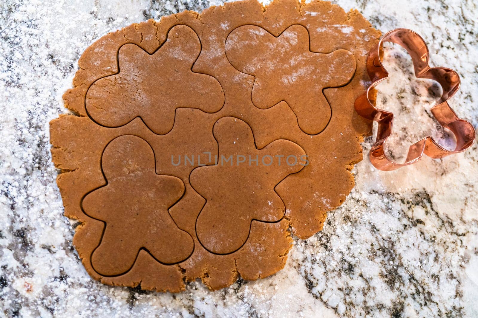 In a contemporary white kitchen, gingerbread cookie dough is skillfully rolled out, setting the stage for a delightful holiday treat.