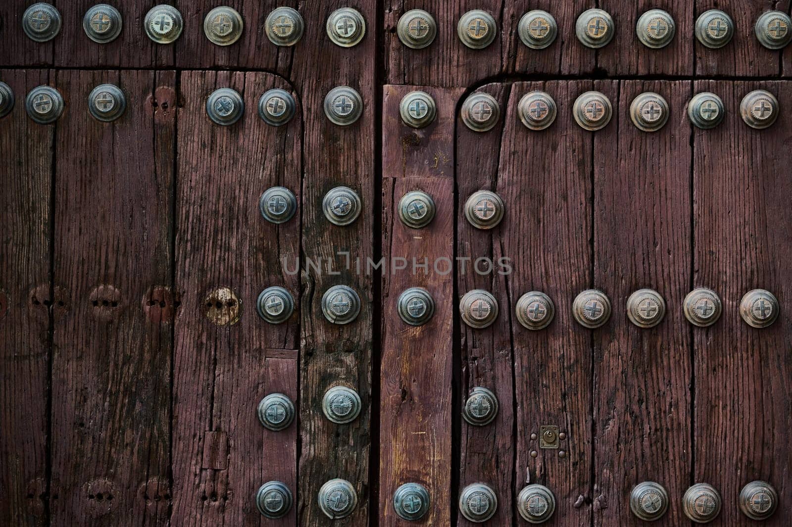 Detailed image of a wooden medieval door with decorative metal studs, showing rich texture and craftsmanship.