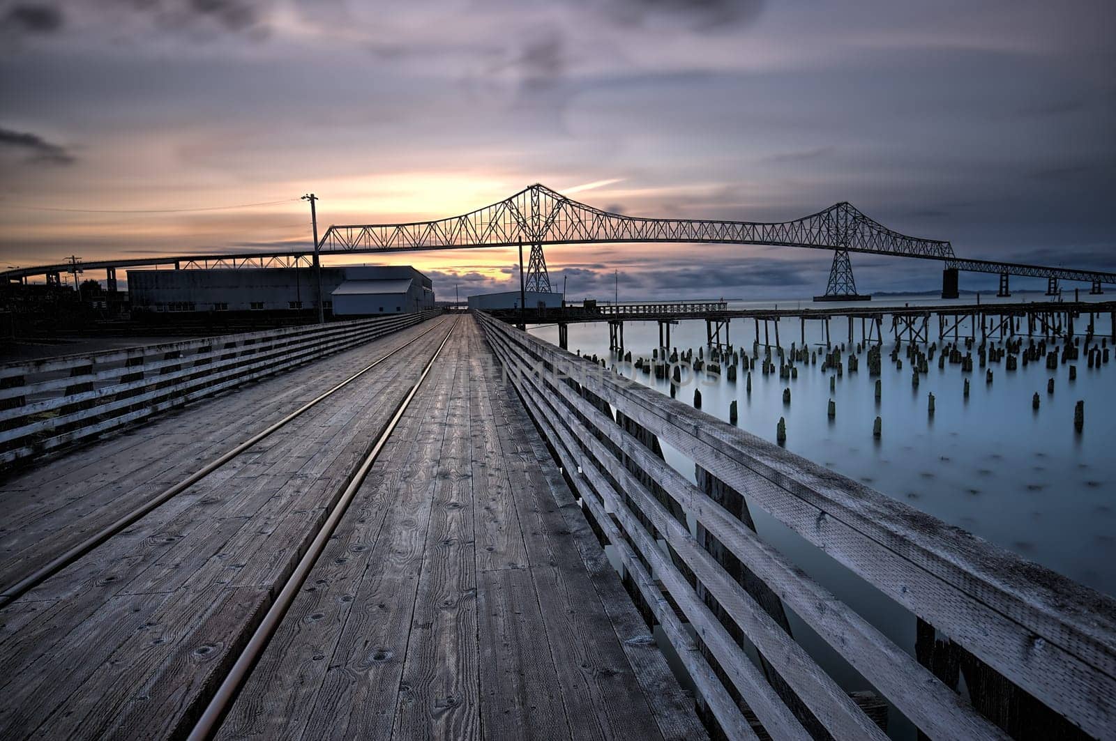 A wooden walkway leads towards the landmark Astoria-Megler bridge in Astoria, Oregon.