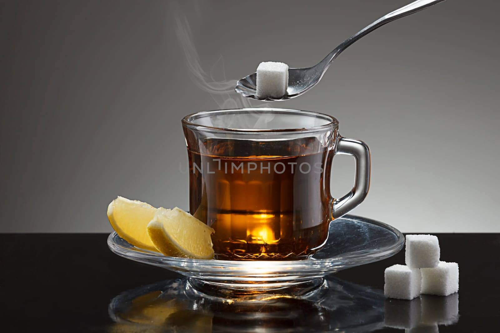 Putting a sugar cube into a cup of hot tea.