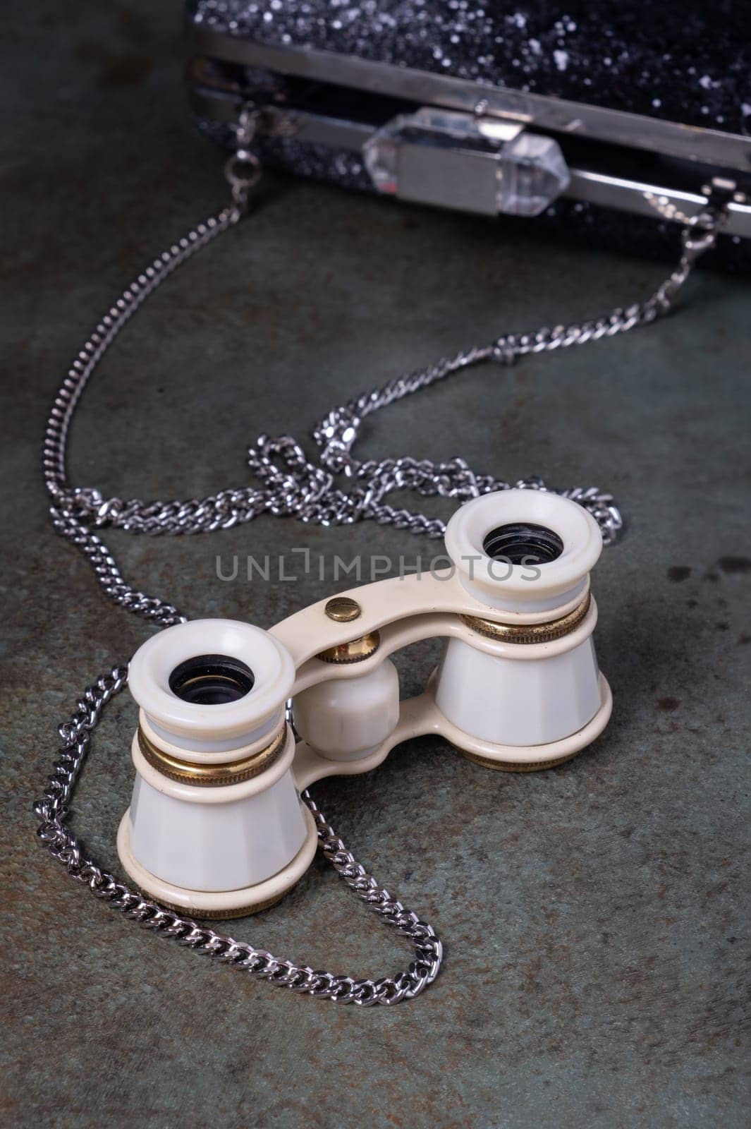 Vintage opera glasses with a black clutch are elegantly displayed. Image evokes nostalgia and luxury