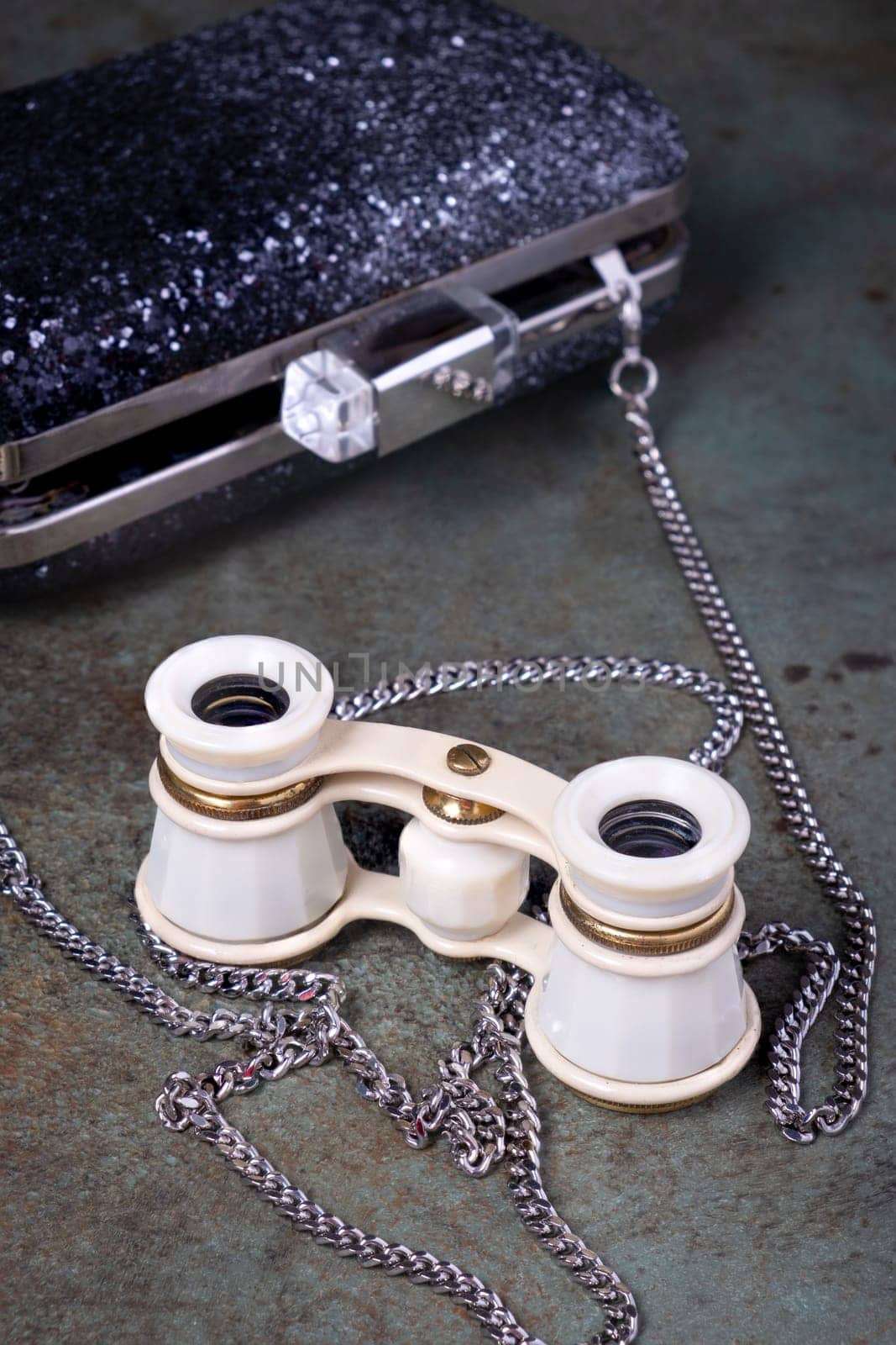 Vintage opera glasses with a black clutch are elegantly displayed. Image evokes nostalgia and luxury