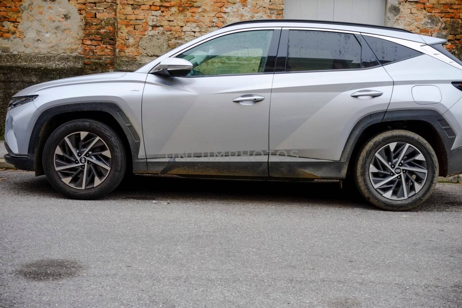 Cremona, Itally - October 6th 2024 Hyundai tucson hybrid suv in silver, displaying its modern design and eco-friendly technology while parked by a brick wall
