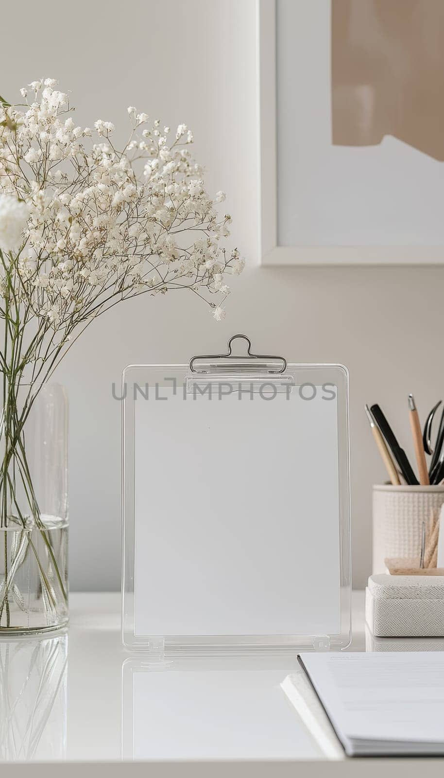 A clean typographic logo sticker on a clear acrylic clipboard, styled on a minimalist desk featuring professional stationery. the design includes a potted plant, a cup, and sunlight casting shadows for an elegant workspace aesthetic.
