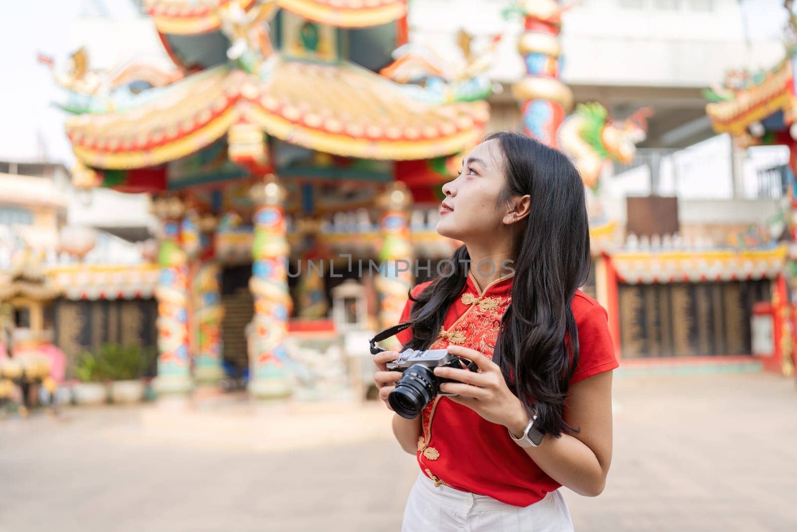A young woman photographs the vibrant shrine during Chinese New Year celebrations capturing cultural worship and joy.