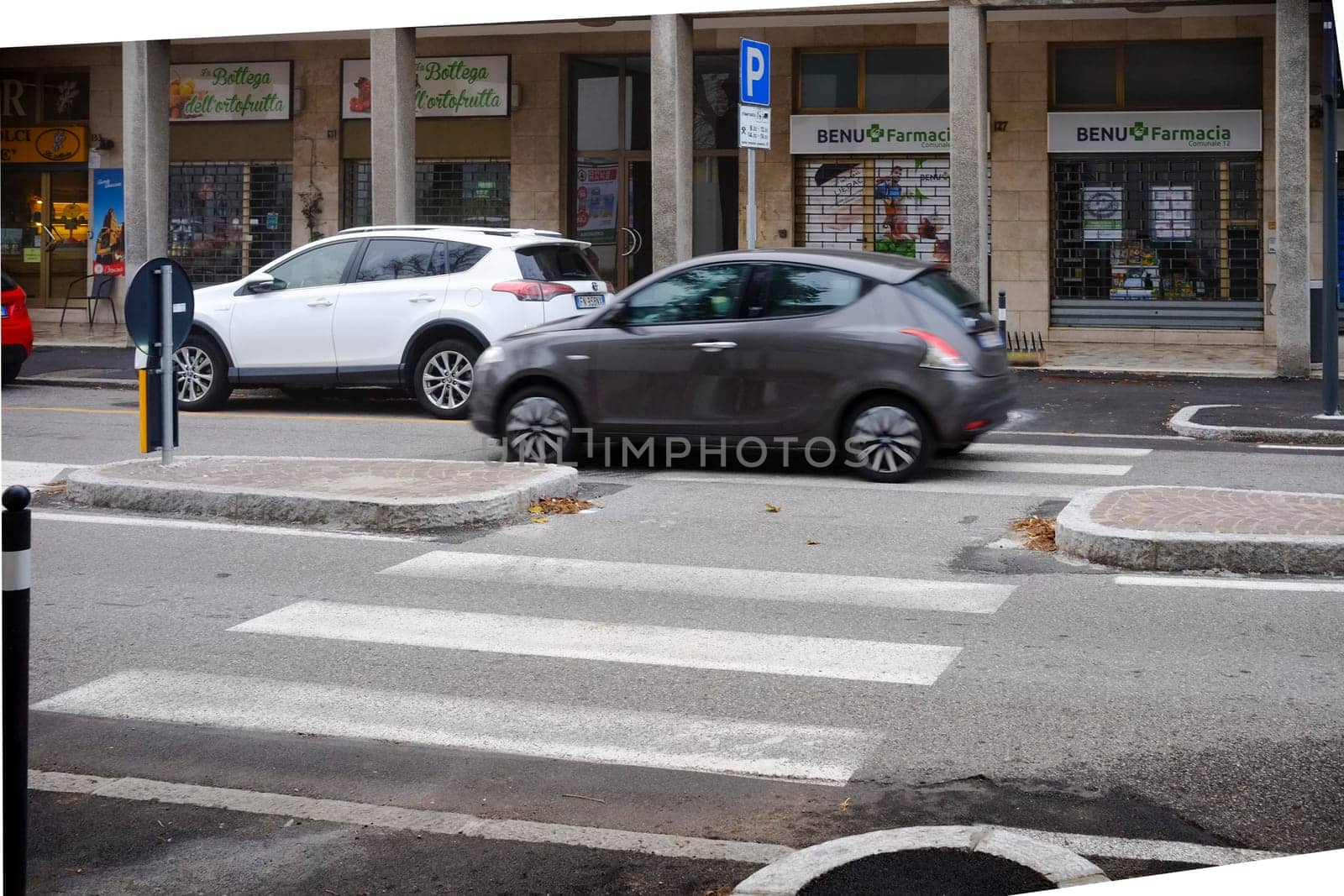 Cremona, Itally - October 6th 2024 Gray lancia ypsilon 1.2 8v 69 hp 2011 driving through pedestrian crossing in urban street