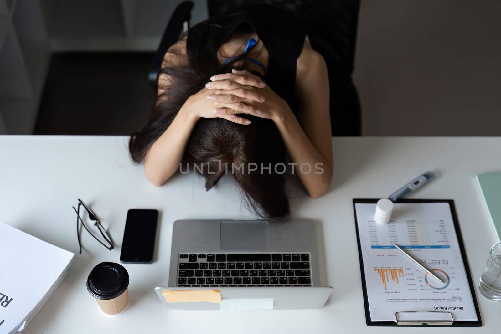 An office worker experiencing stress and fatigue at their desk, surrounded by work materials in a corporate setting.