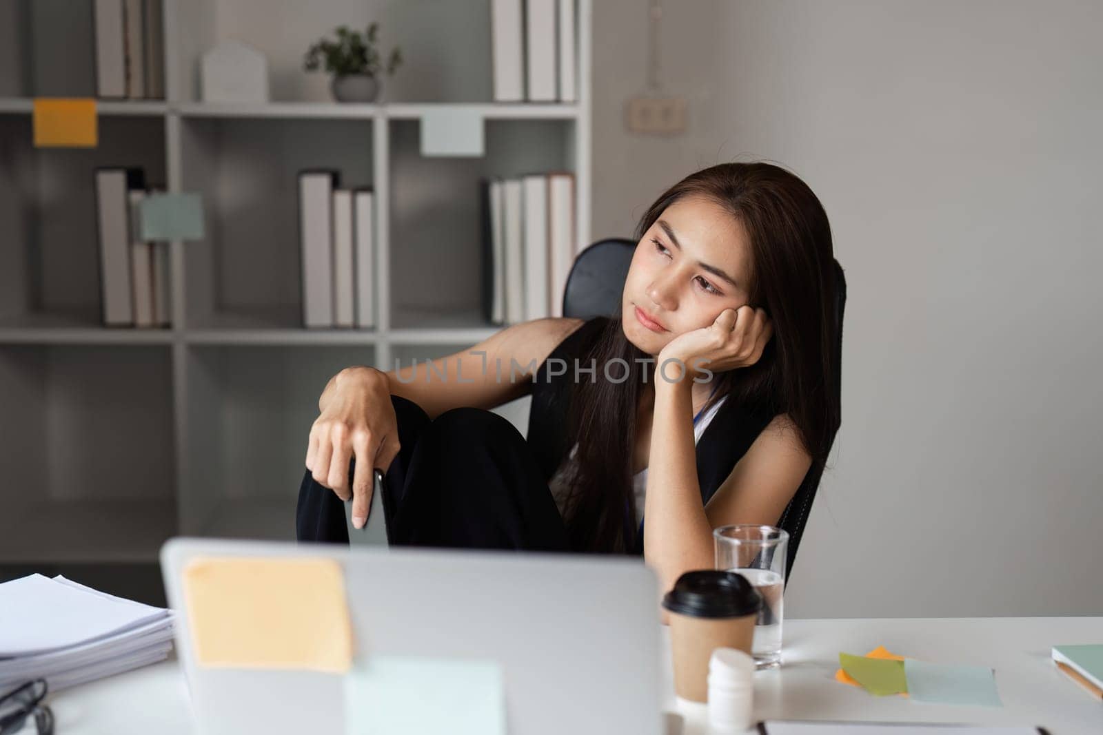 A stressed office worker sits at a desk with a laptop and coffee, reflecting the pressures of a modern work environment.