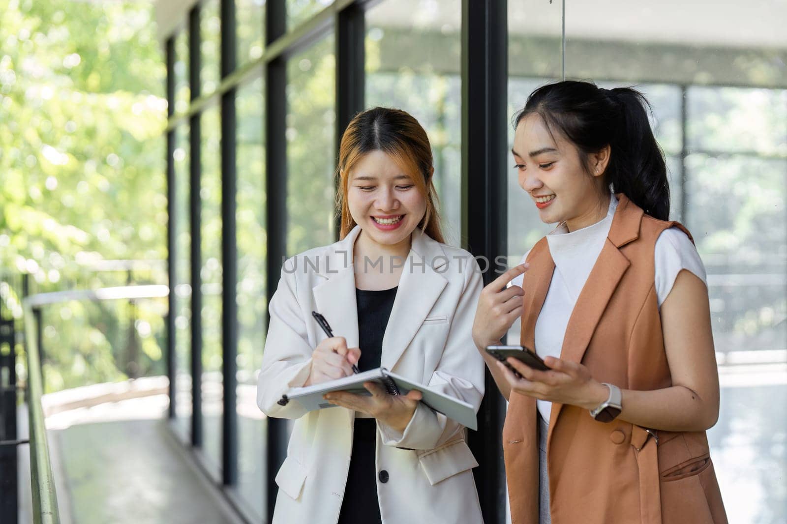 Two business professionals discussing collaboration strategies in a modern office setting, using digital devices and documents.