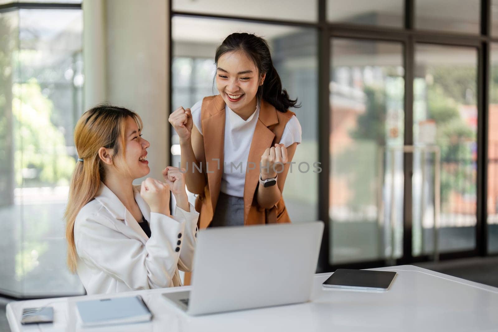 Two successful businessmen happily celebrating a business achievement in a modern office setting, showcasing joy and success.