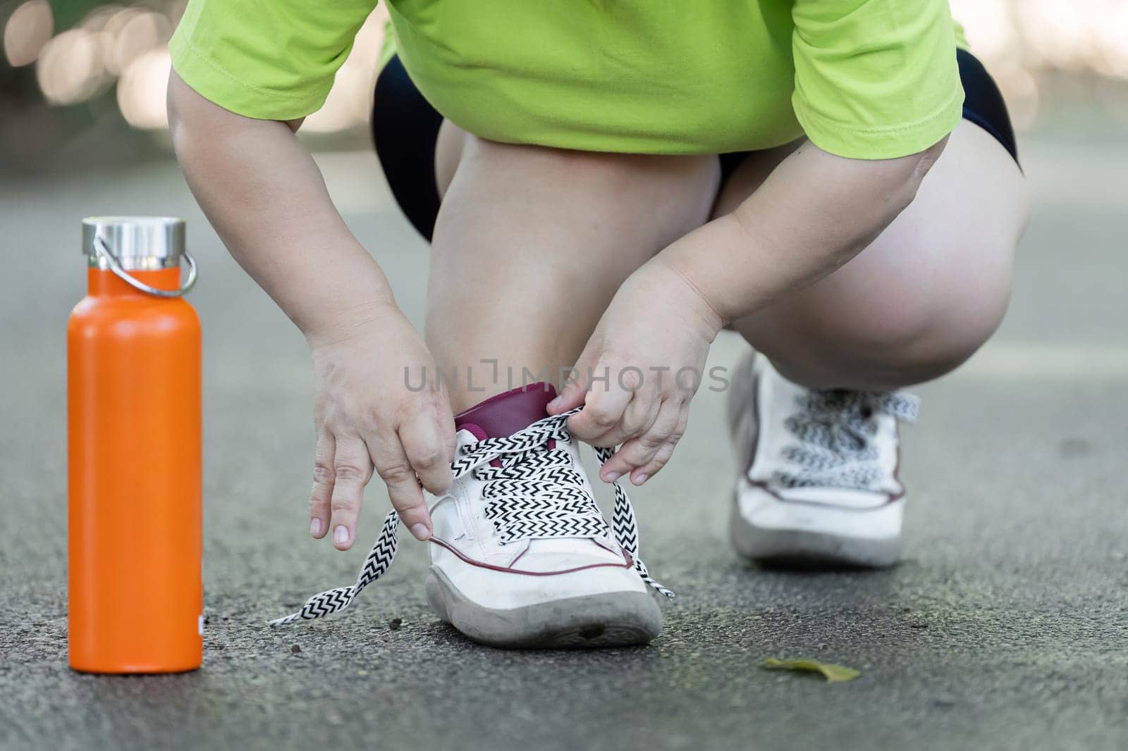Petite woman jogging in a park, wearing vibrant sportswear, promoting fitness and a healthy lifestyle.