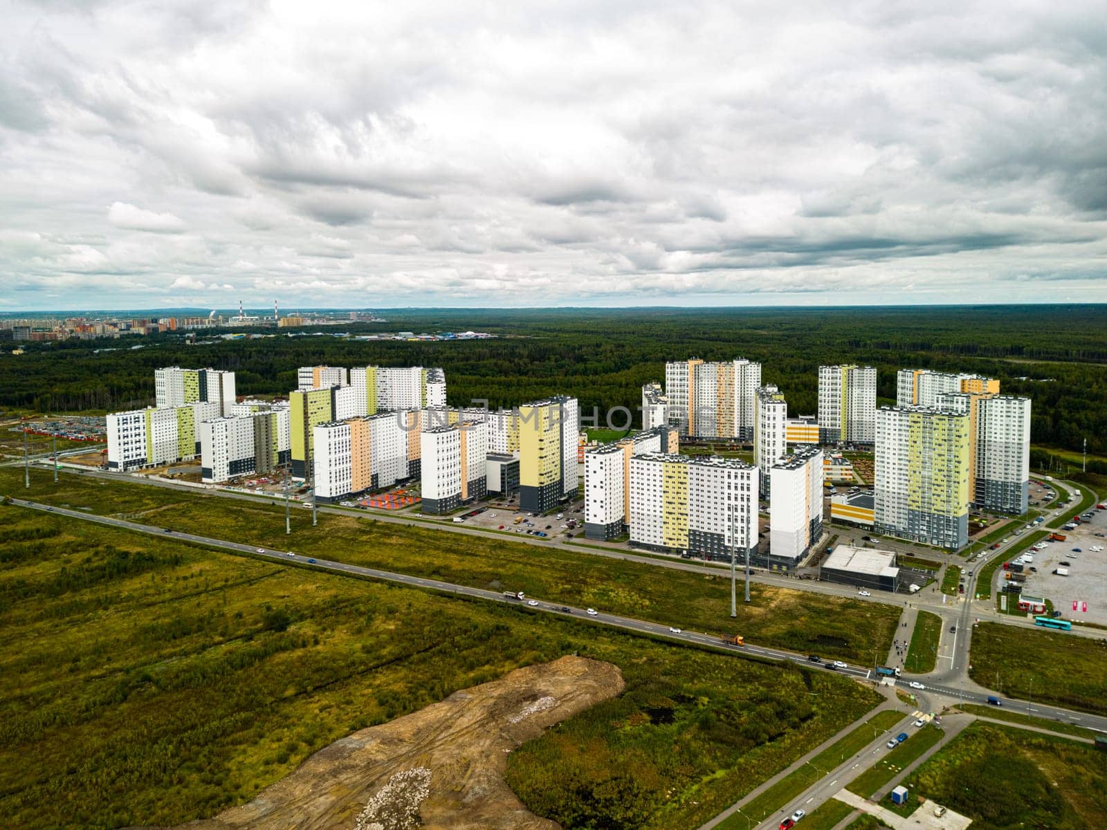 An expansive aerial view showcases modern residential buildings set in an urban area, embraced by vibrant lush greenery
