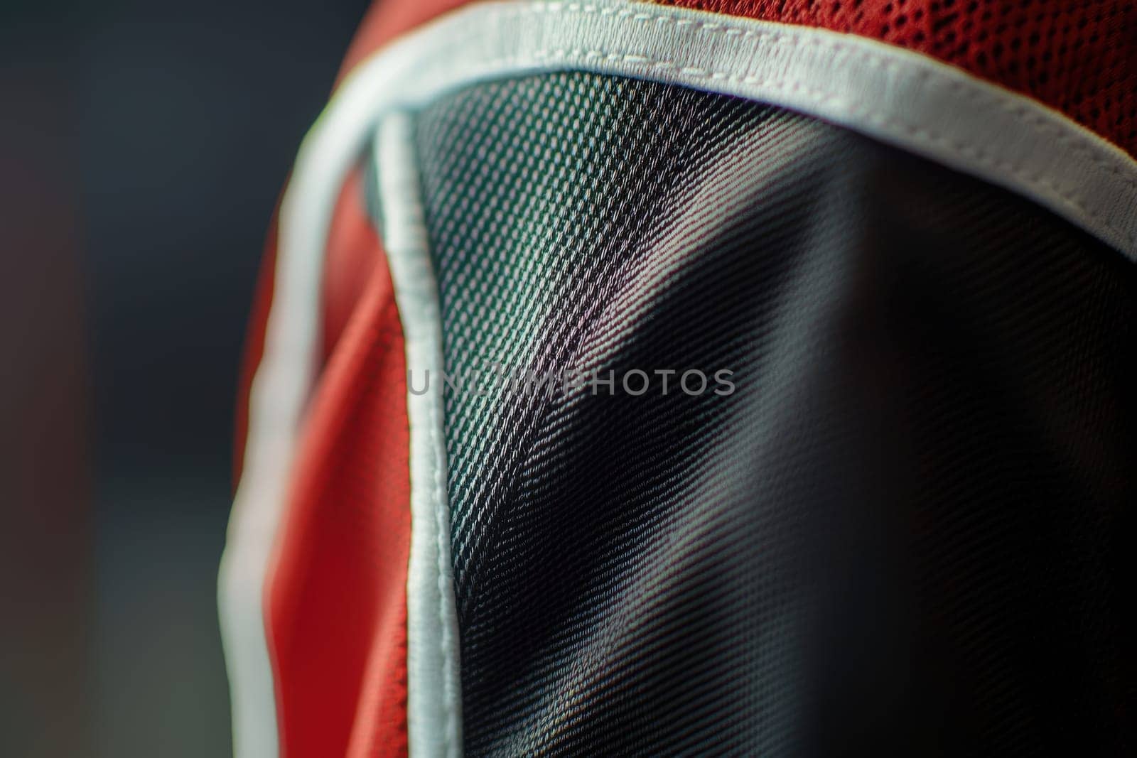 Close-up view focused on the sleeve area of a sports jersey, showcasing precise stitching and logo placement. the blurred studio background highlights the texture and design elements, bringing attention to the garments craftsmanship.