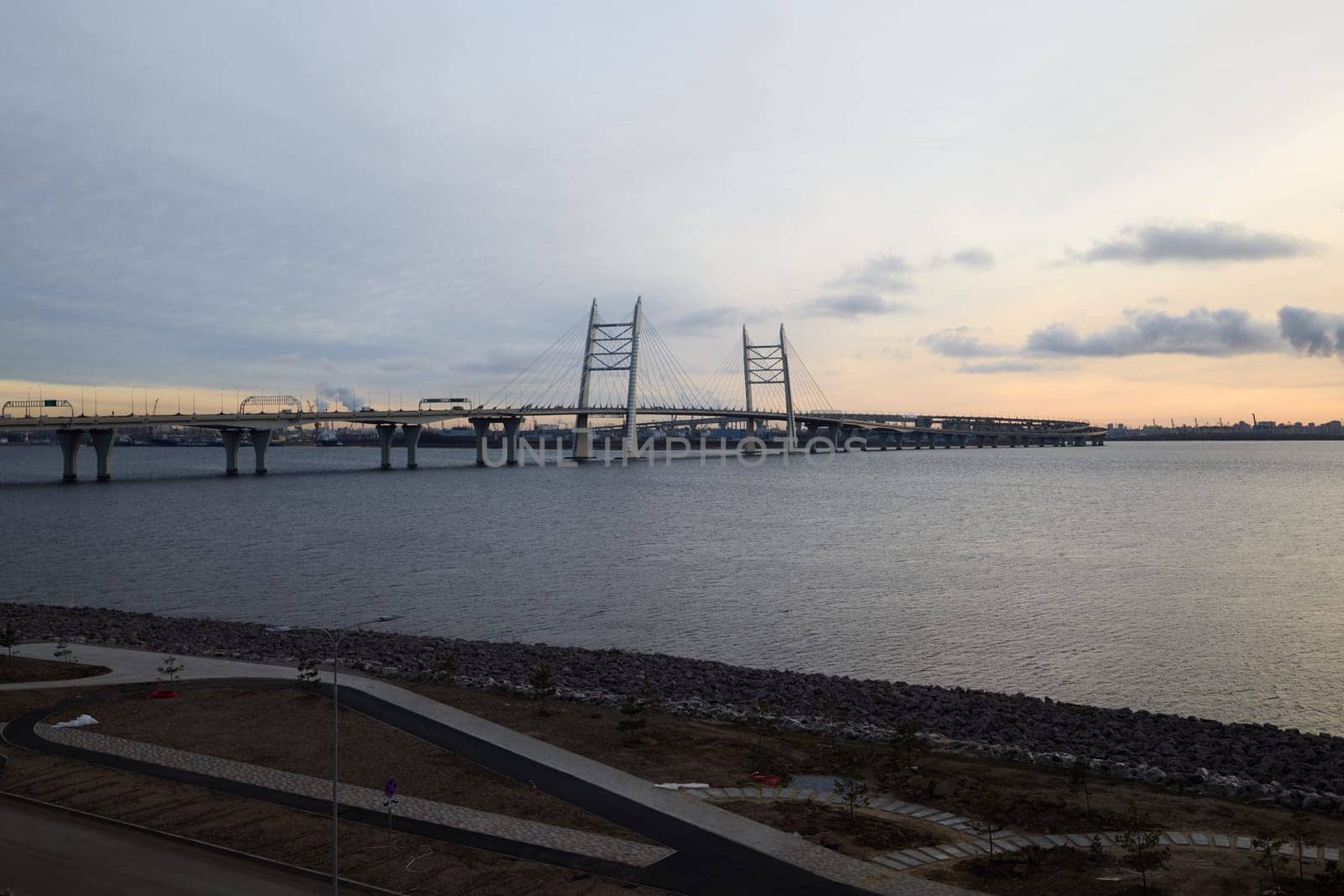 A breathtaking sunset casts vibrant colors that beautifully illuminate a suspension bridge spanning tranquil waters