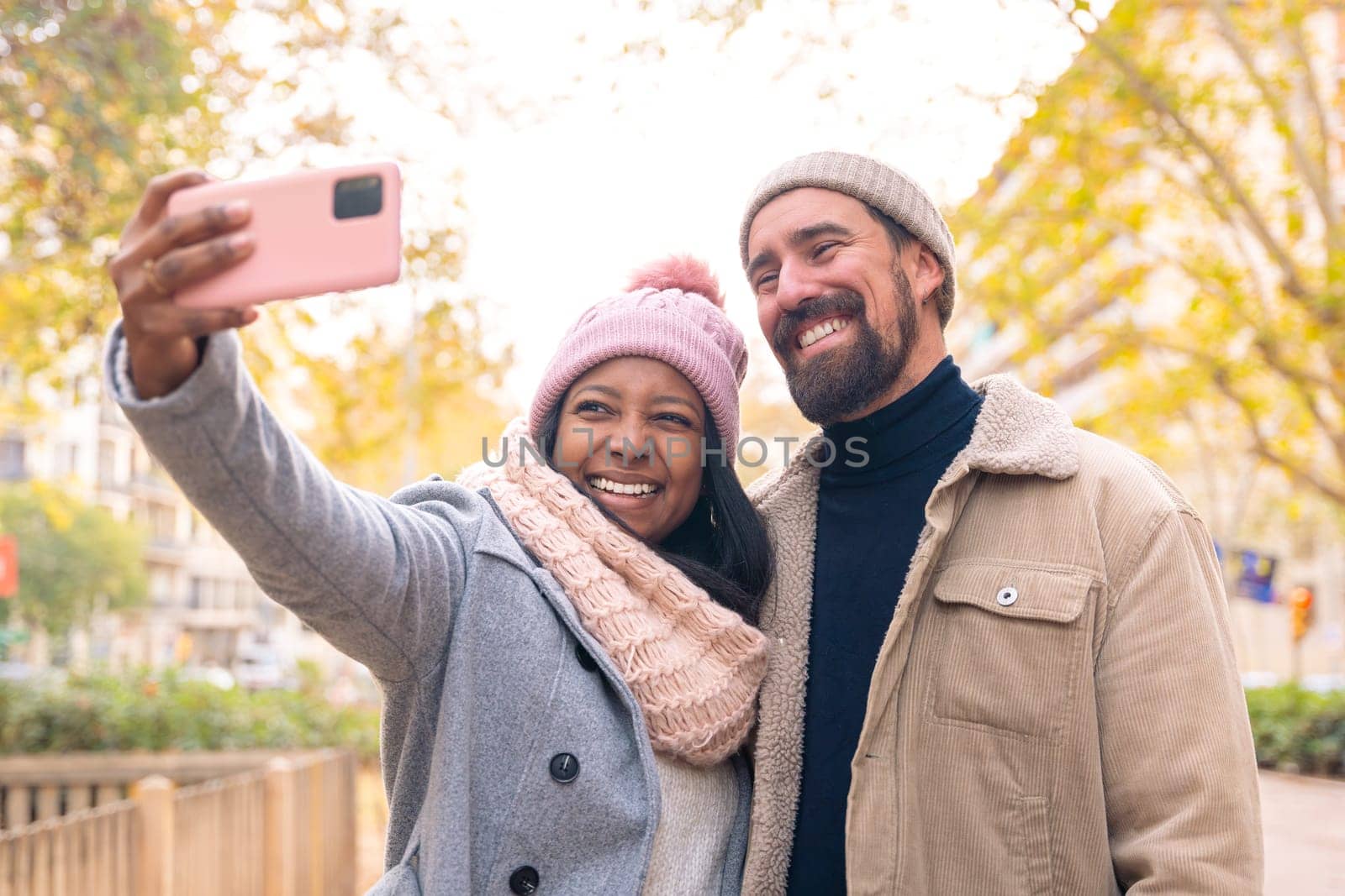 Happy friends taking photos on smartphone having fun outdoors. Spouses enjoy the weekend in a trendy shopping mall.
