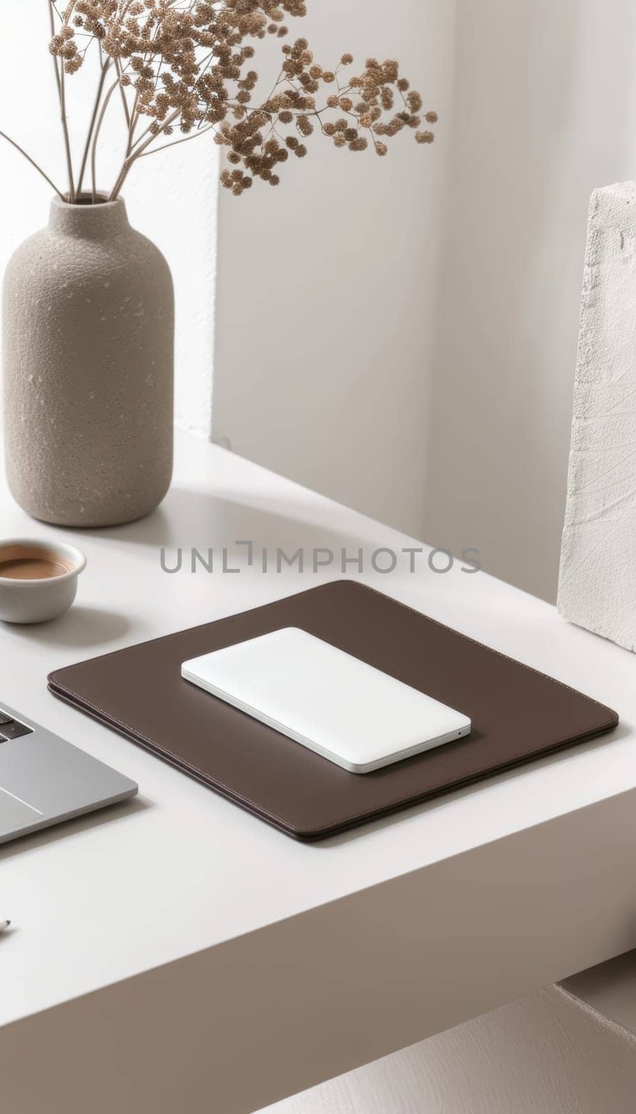A stylish mocha mousse laptop sleeve featured on a modern white desk, accompanied by matching tech accessories, like a wireless mouse, smartphone, eyeglasses, mouse pad, and a takeaway coffee cup. perfect for tech-savvy professionals.