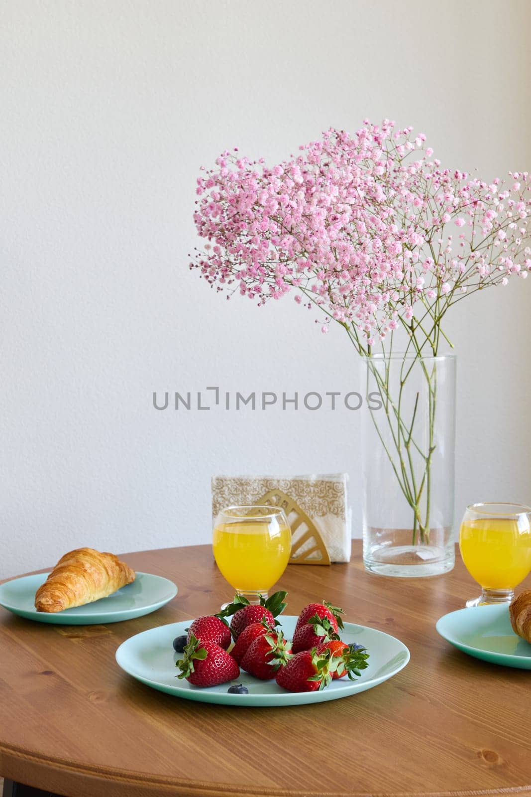 A beautifully arranged breakfast with fresh strawberries, a flaky croissant, and refreshing orange juice