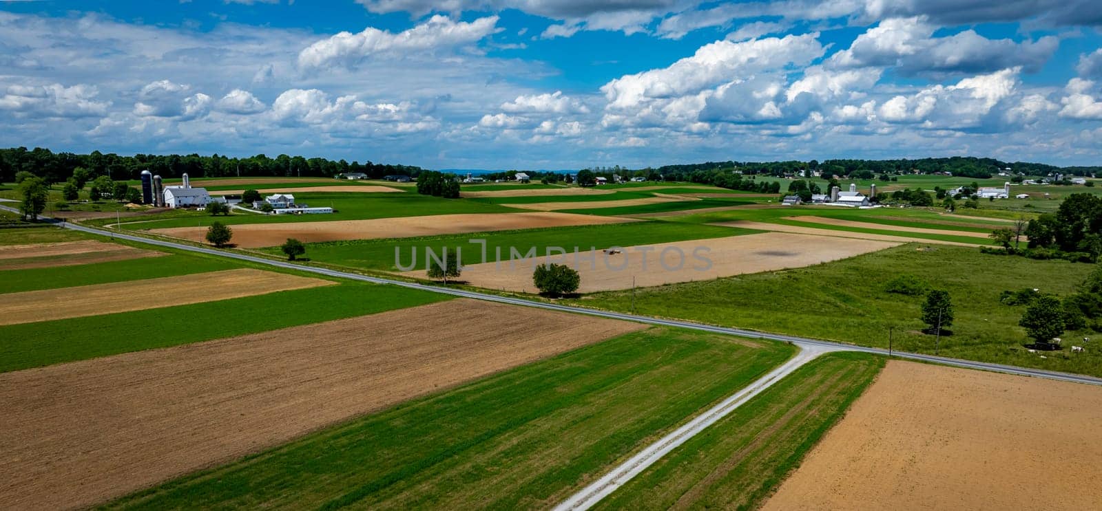 Vast agricultural fields dominate the landscape, showcasing a mix of green crops and brown earth.