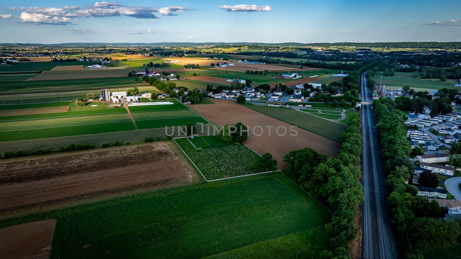 Vast fields stretch across the Pennsylvania countryside, showcasing a mix of agricultural land, patches of green, and distant hills, all bathed in the warm glow of the setting sun.