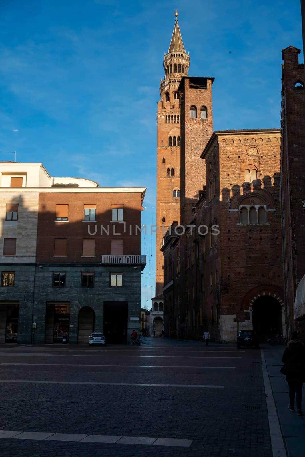 Cremona, Italy - November 27th 2024 The torrazzo bell tower of cremona cathedral rises majestically over piazza comune in the warm morning light