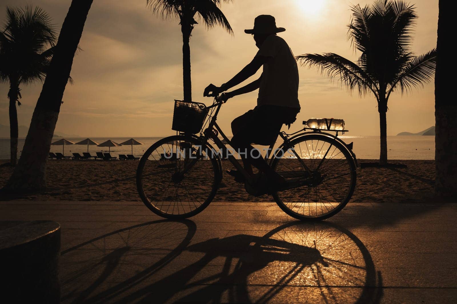 silhouette of cyclist at sunset ride along seashore summer beach at yellow evening horizon sea sunset