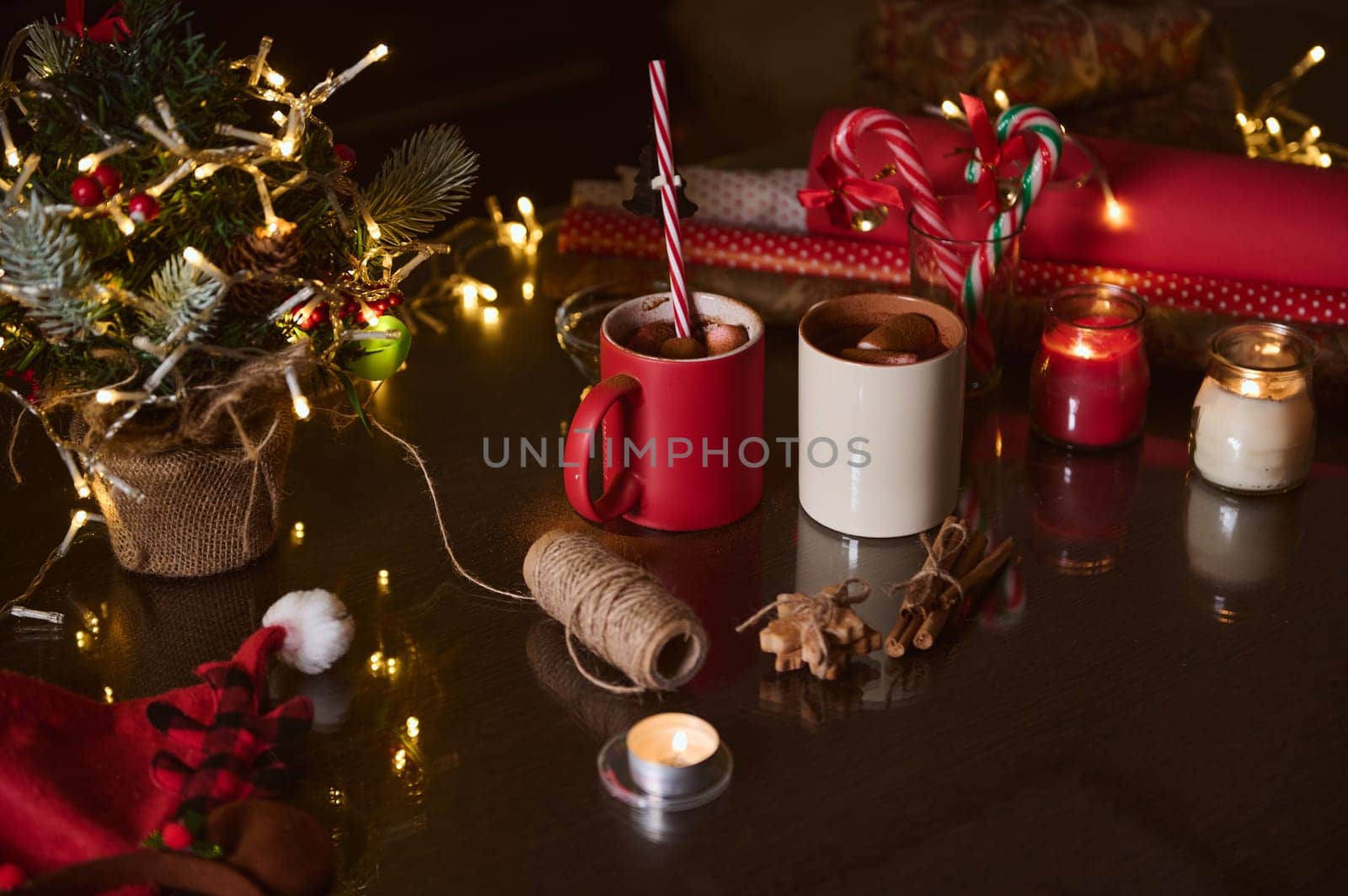 Festive table setting with warm beverages, Christmas decorations, and candles to create a cozy holiday atmosphere.