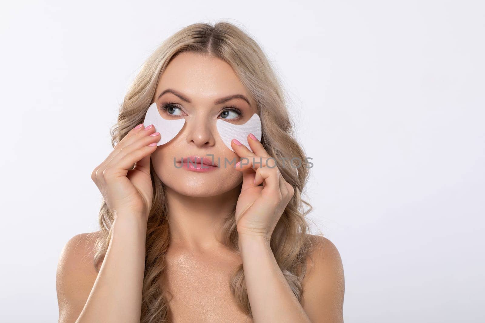A woman applies eye masks designed for hydration and skincare while enjoying a bright and cheerful setting