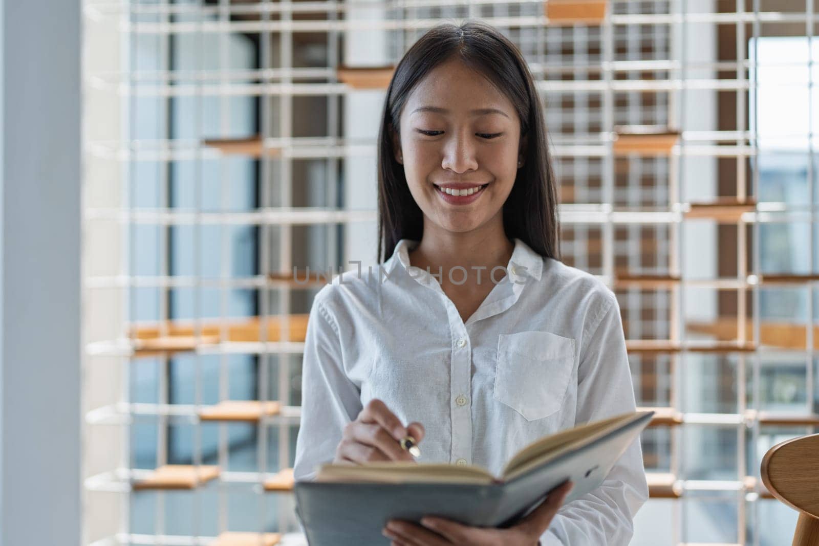 A young woman engages with a book in a bright, stylish indoor setting, reflecting concentration and joy while showcasing a passion for learning and creativity.