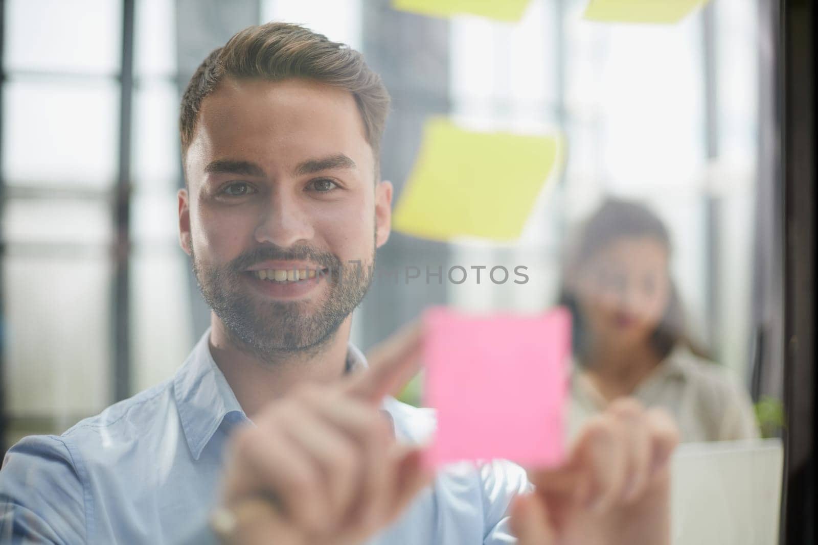 businessman is working on a project. Business man pointing at a note on the glass wall