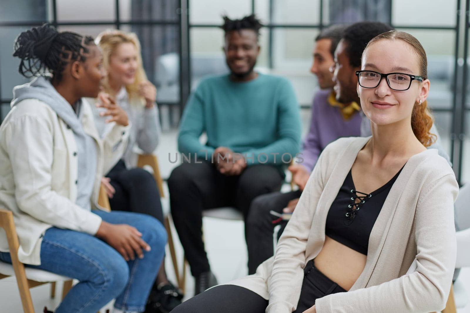 Smiling businesswoman looking at camera at seminar with her colleagues near by