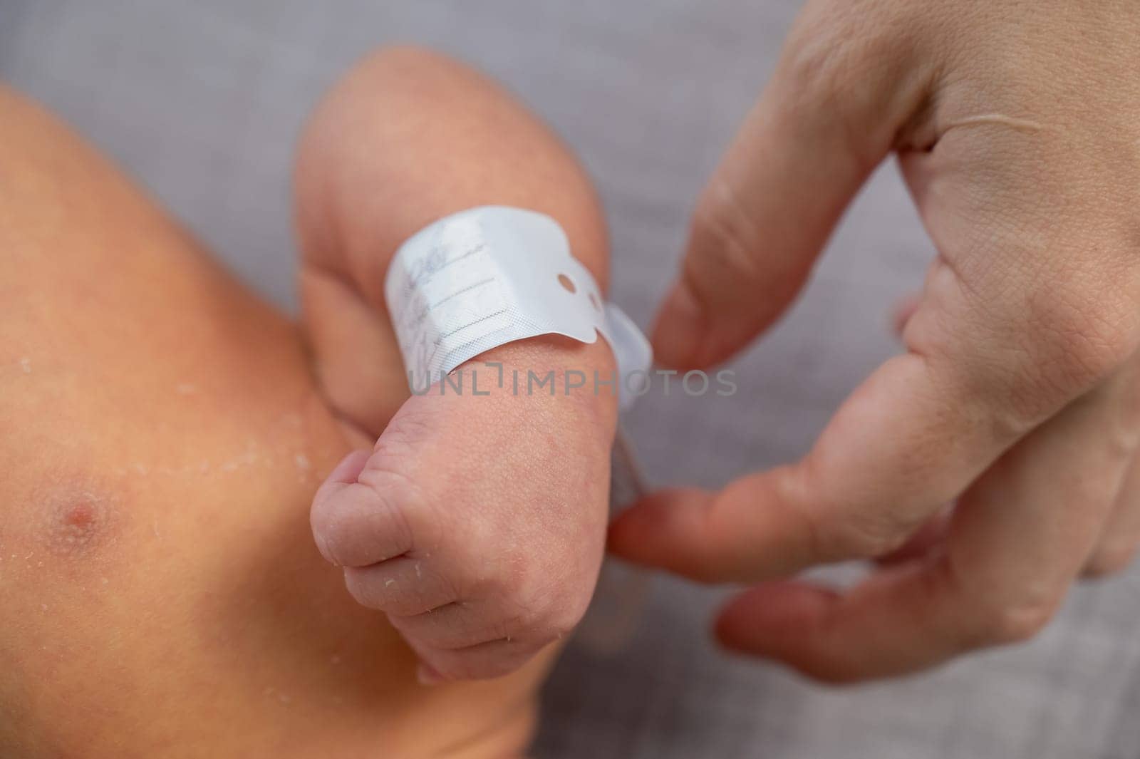 Woman holding newborn by tag on hand