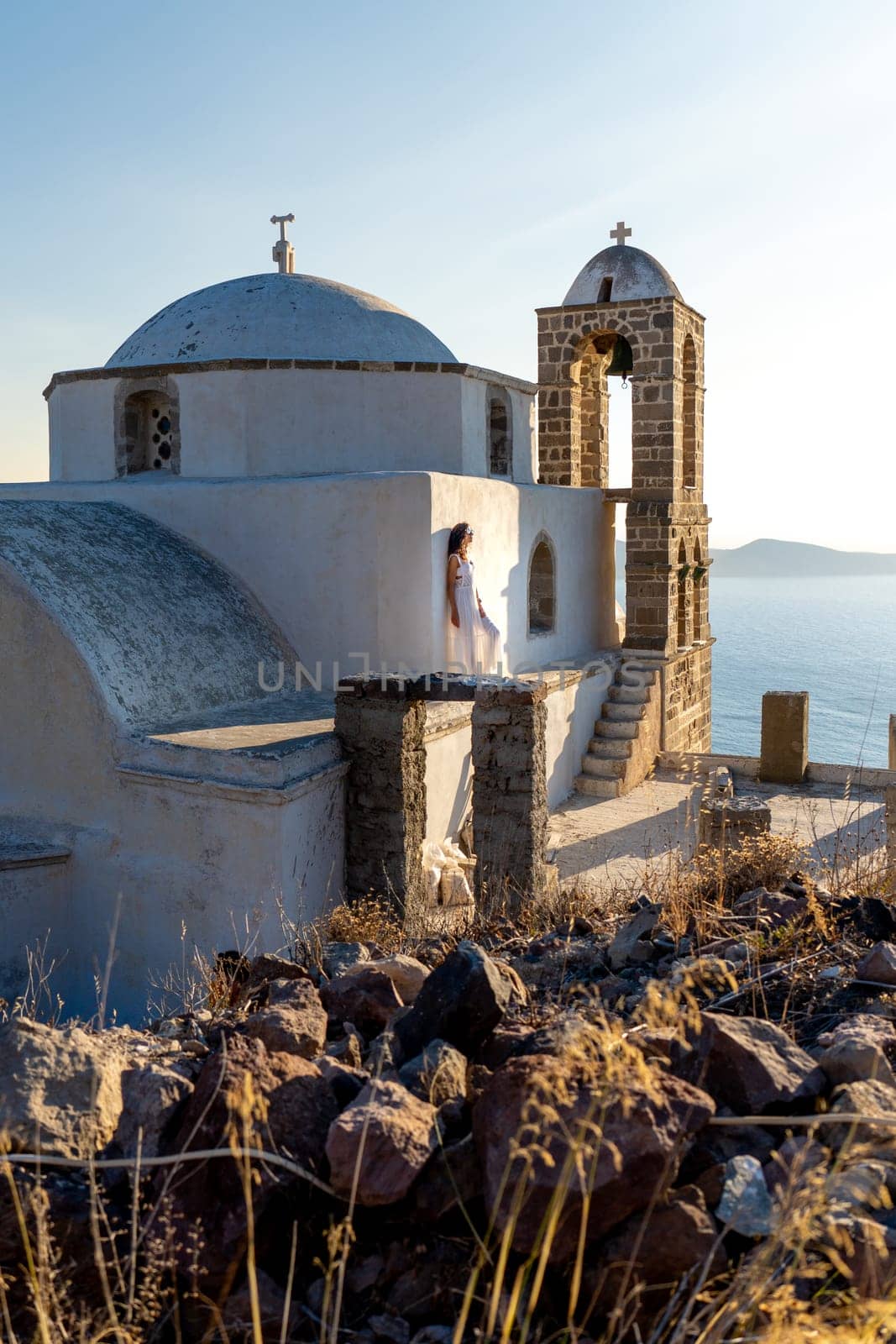 Woman in white dress looking at the sea in church Panagia Thalassitra, Plaka, Milos