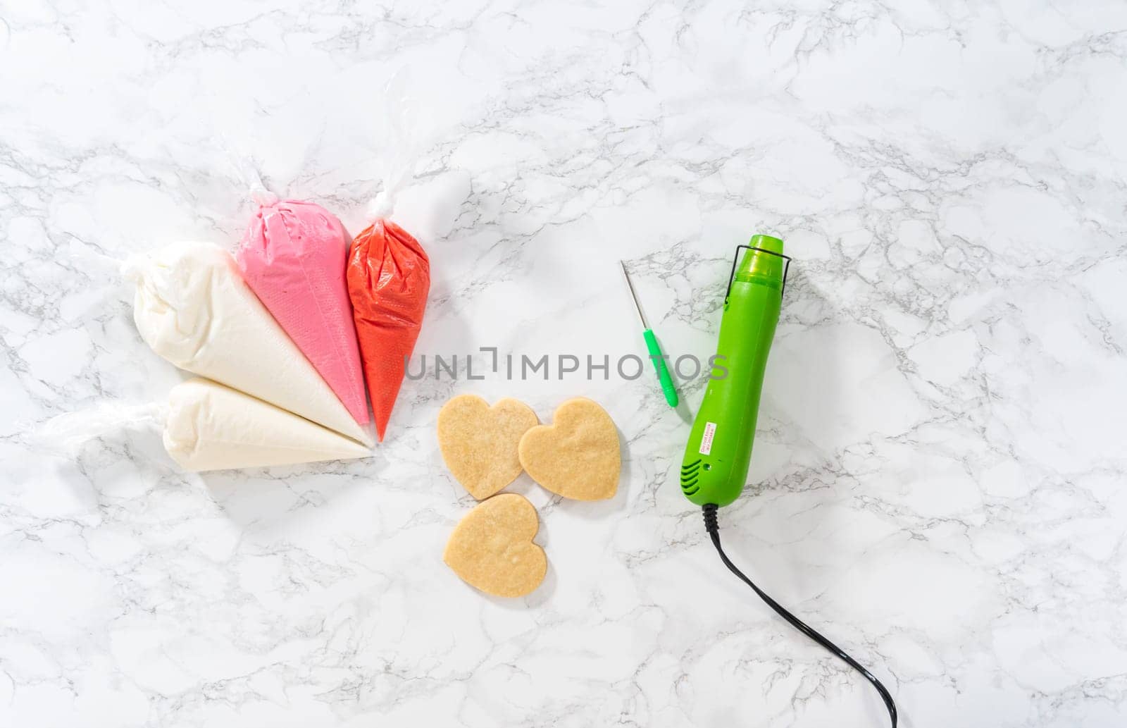 Flat lay. Homemade royal icing in piping bags ready to decorate sugar cookies on the kitchen counter.