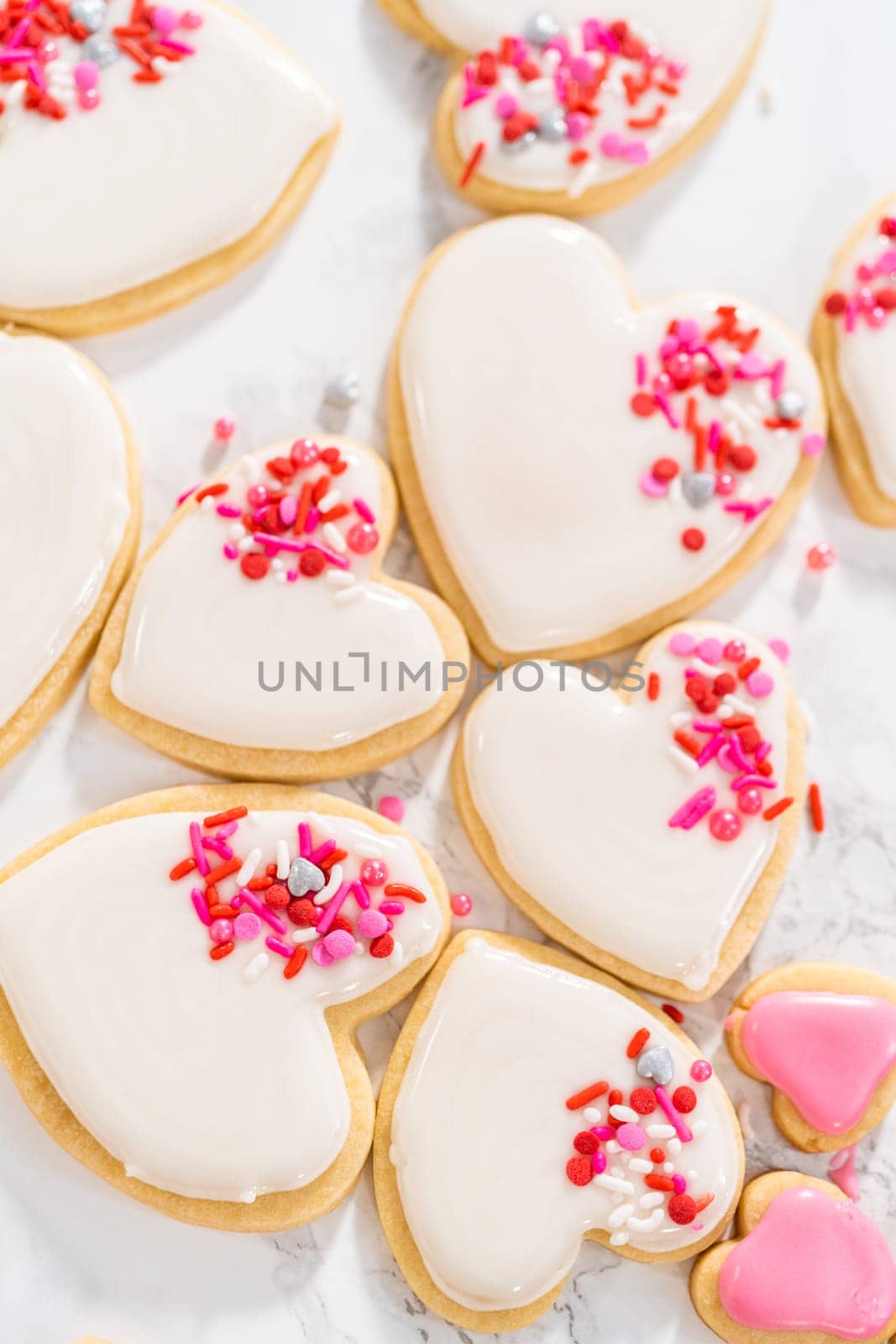 Decorating heart-shaped sugar cookies with pink and white royal icing for Valentine's Day.