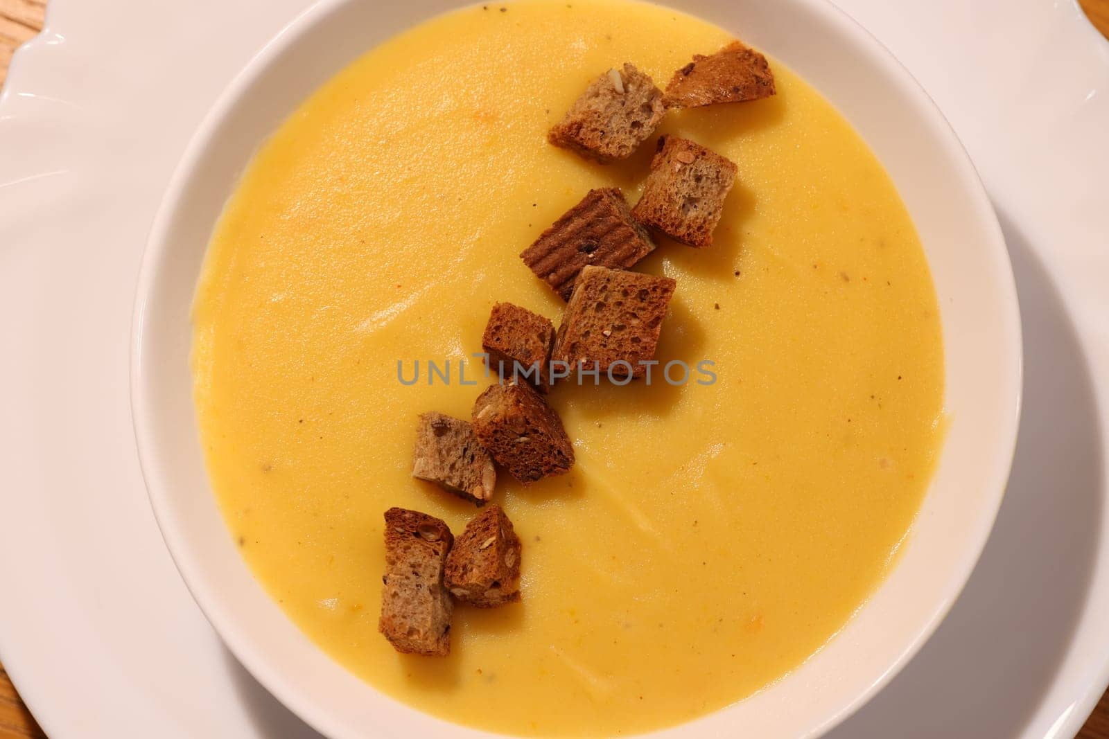 A vibrant bowl of creamy pumpkin soup topped with crunchy croutons, perfect for seasonal comfort and warmth
