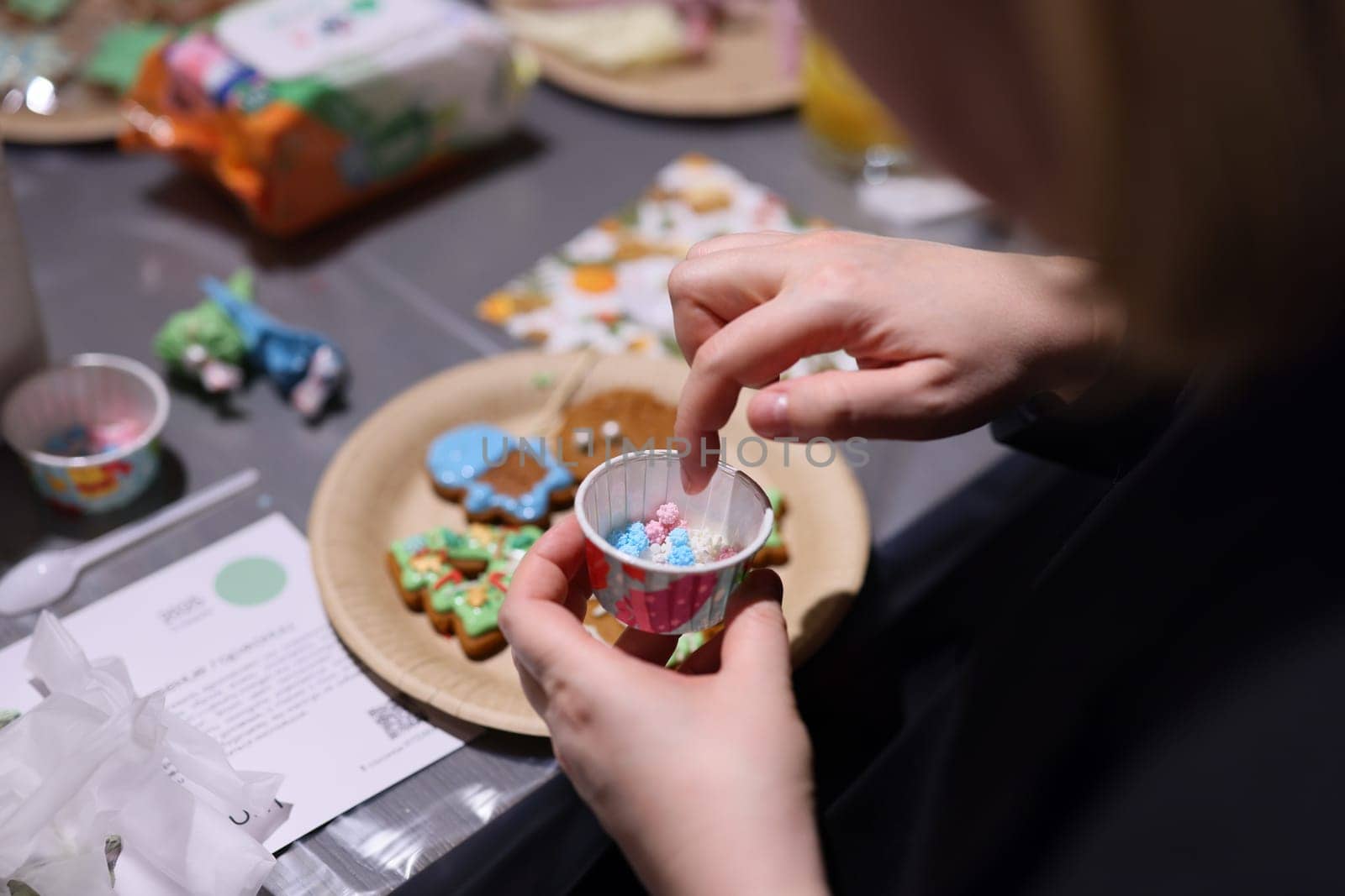 A delightful closeup of hands carefully decorating vibrant festive cookies with colorful sprinkles and icing