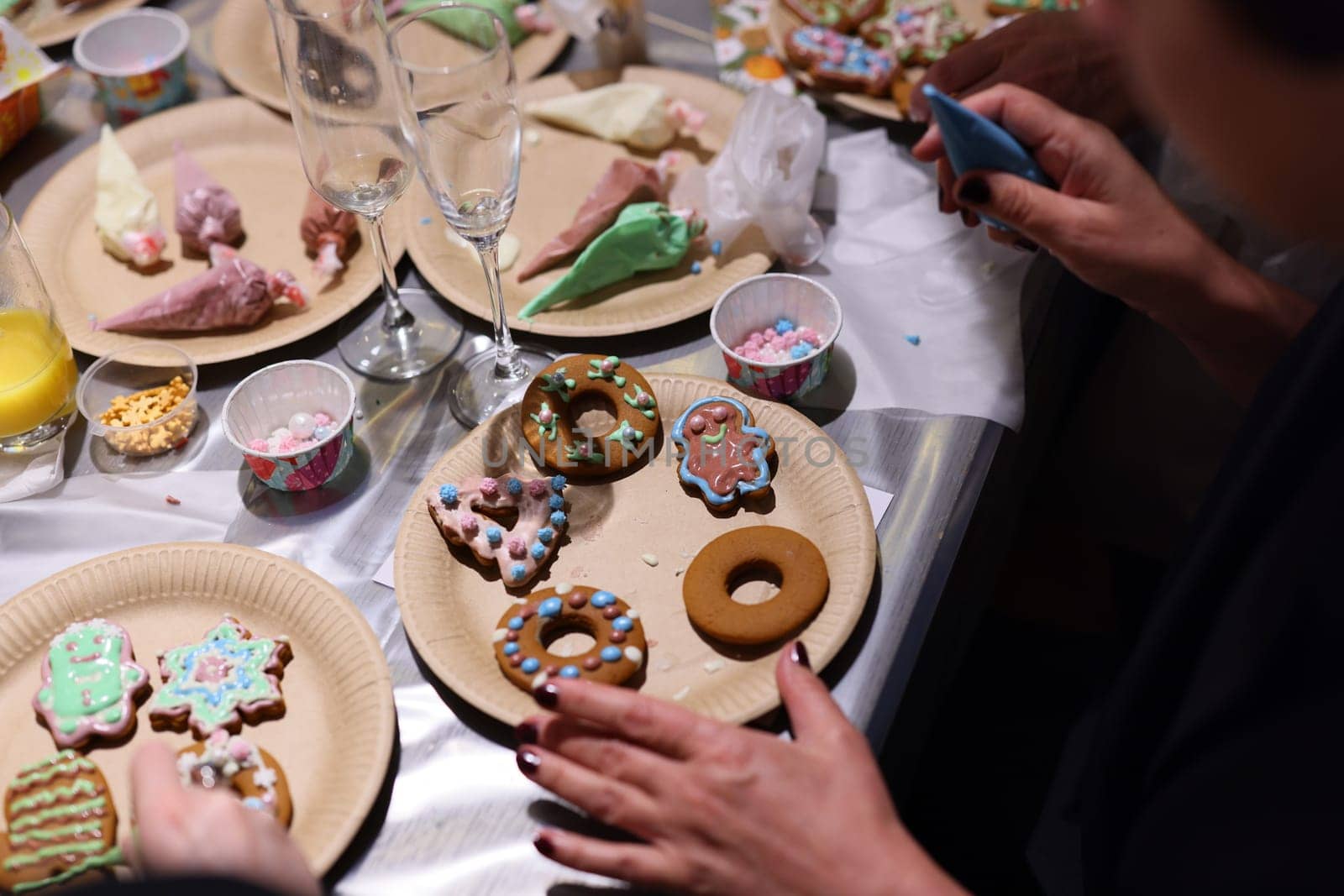 People are joyfully decorating delicious cookies with vibrant icing and toppings at a fun festive event