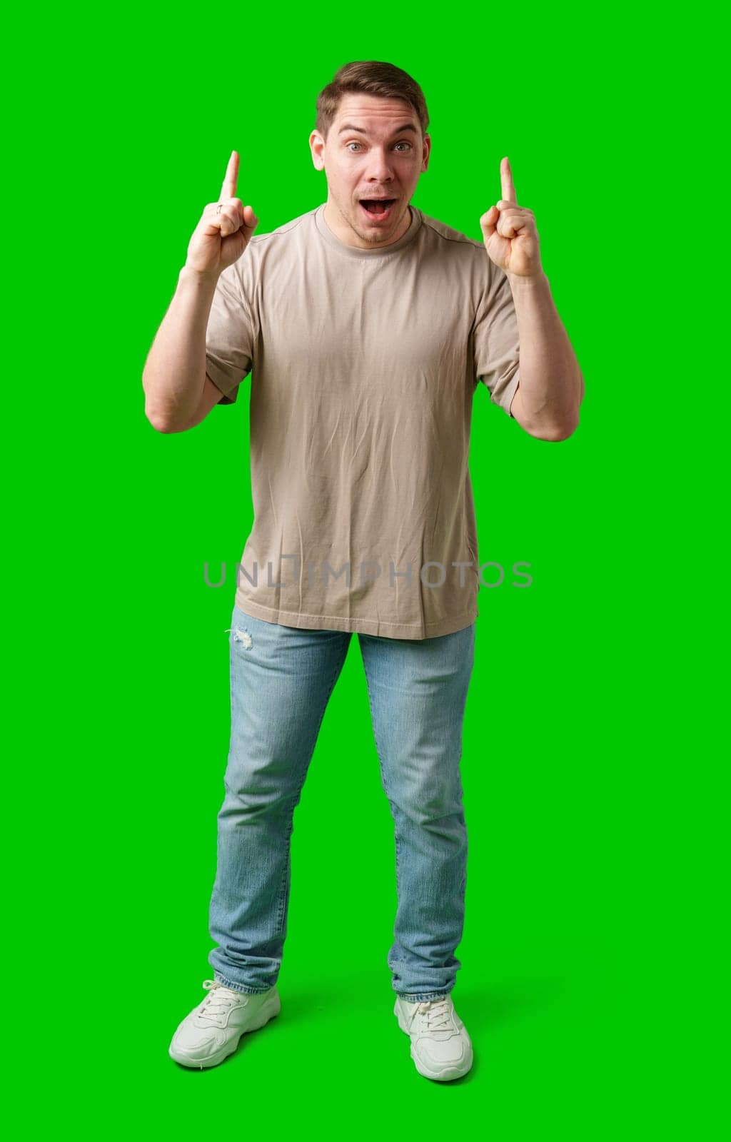 Enthusiastic man pointing upwards against a vibrant green background in studio