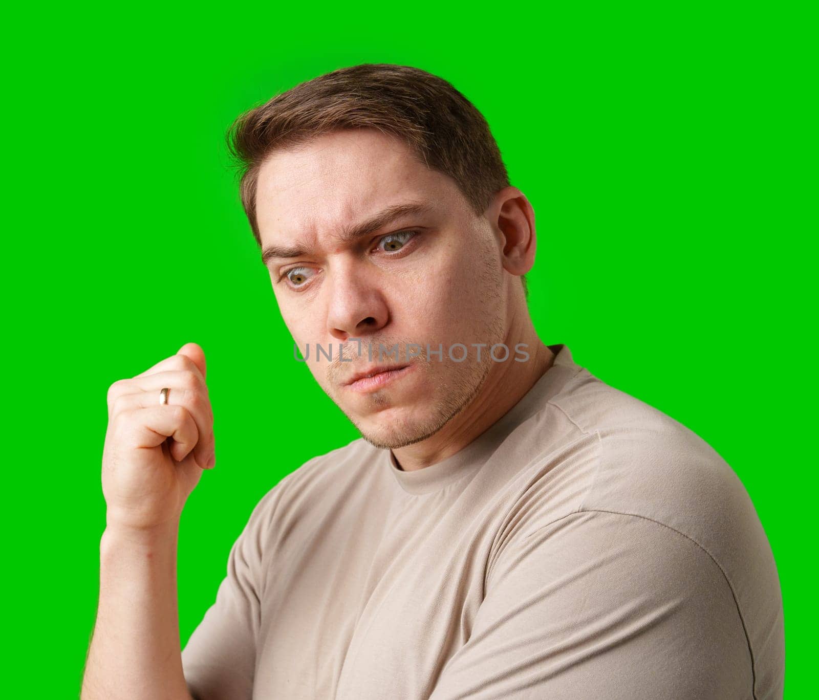 Thoughtful man gestures against a green background in studio
