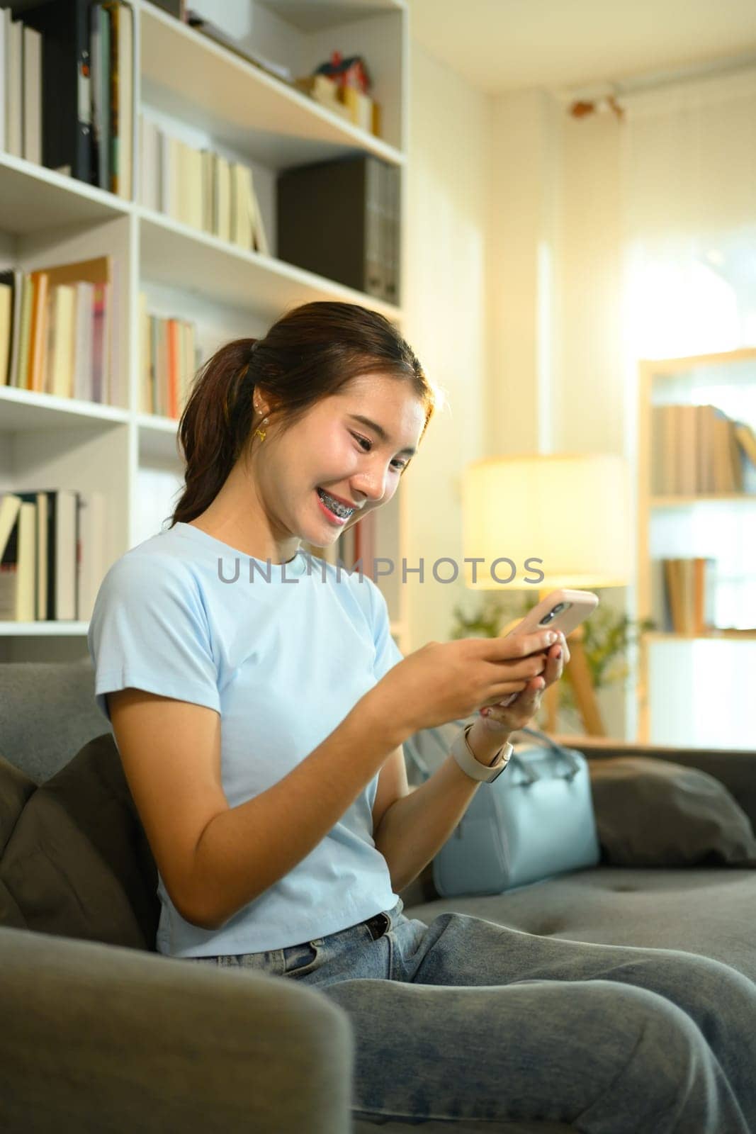 Smiling young woman while checking her smartphone in a stylish living room.