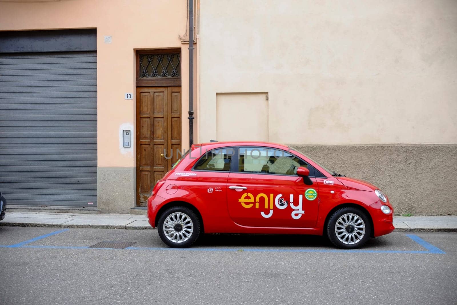 Cremona, Itally - October 6th 2024 Bright red fiat 500 enjoy carsharing vehicle parked on a designated parking spot in a residential area