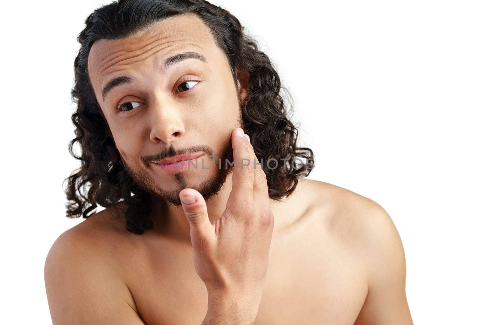 Young man with curly hair thoughtfully posing against a plain background in a studio setting