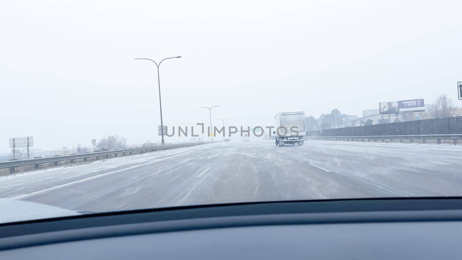 Denver, Colorado, USA-January 15, 2024-Several vehicles face blinding snowfall and slippery conditions while traveling on an interstate, with the storm reducing visibility and the roads boundaries barely discernible.