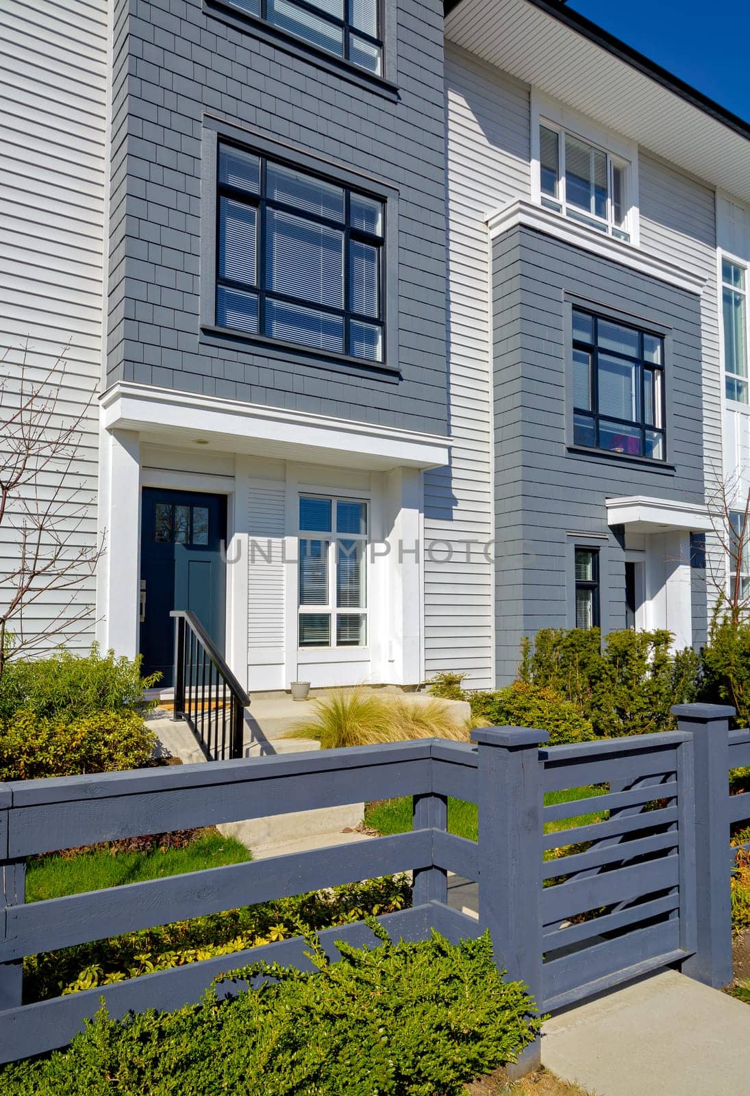 Entrance of brand new residential townhouse with wooden fence and small front yard