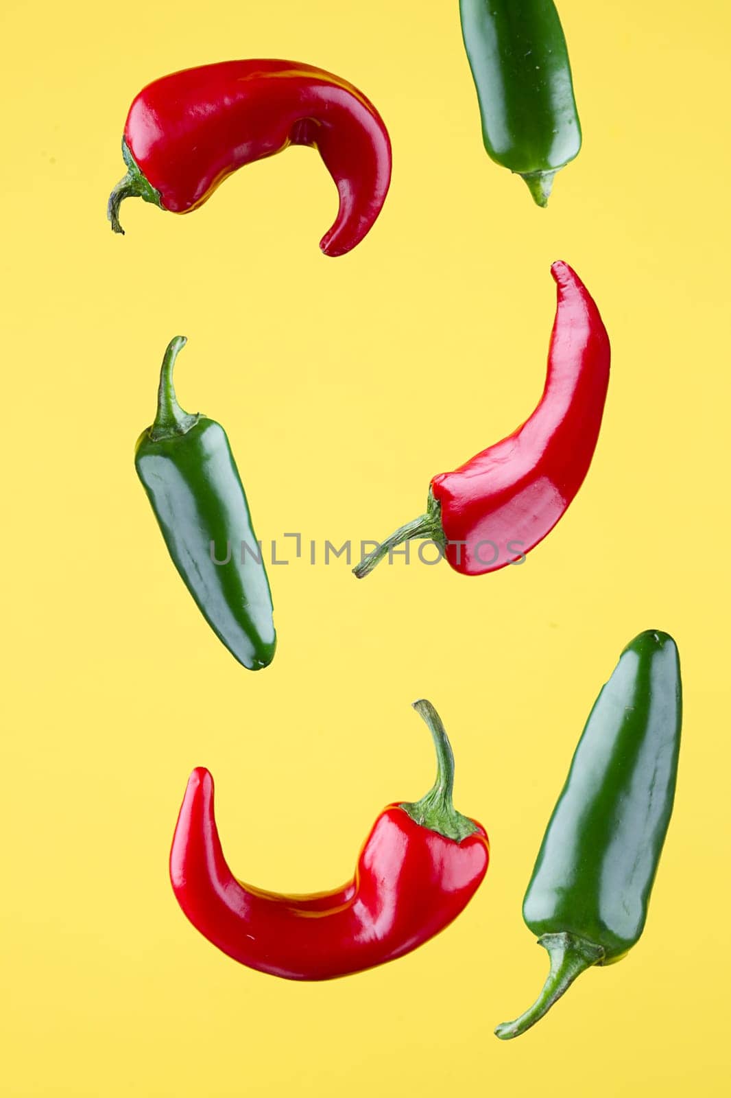 Red and green jalapeno peppers set against a yellow background.