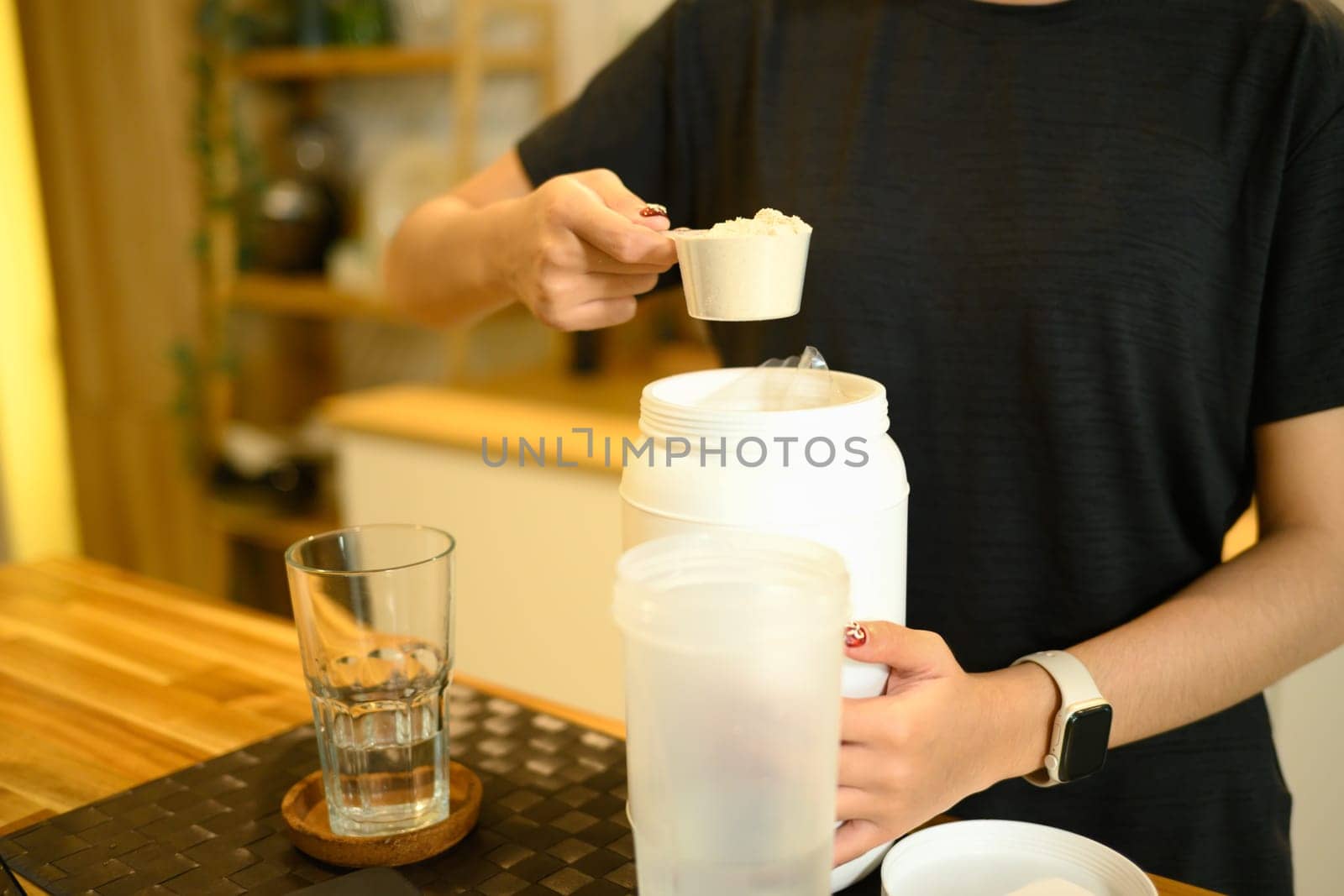 Young asian woman preparing protein shake after workout in a home kitchen.