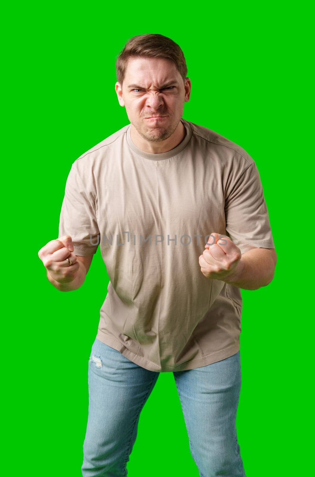 Man expressing intense frustration while standing against a bright green background in studio